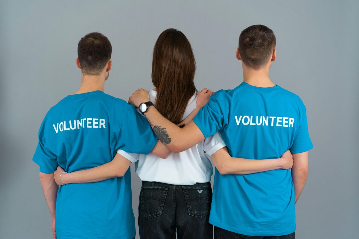 Three volunteers from behind, symbolizing unity and teamwork.